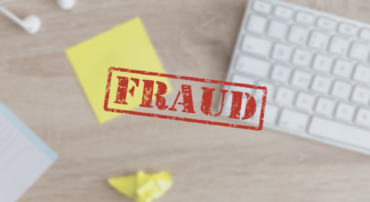 Red FRAUD stamp over a blurred desk with a keyboard and sticky notes, representing imposter syndrome at work.